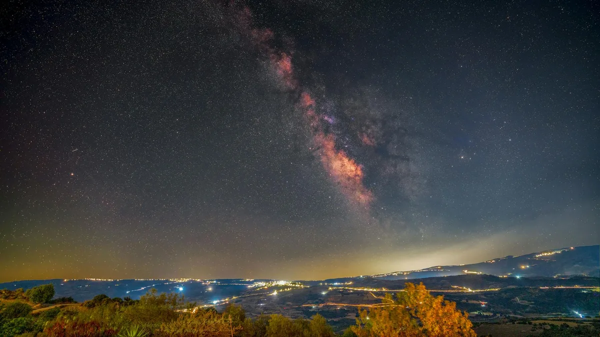 Milchstraße über hell erleuchteter Landschaft bei Nacht – atemberaubender Blick auf die Weite des Weltraums