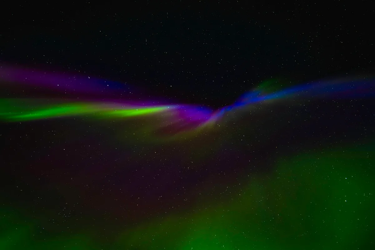 Aurora boreale vivida nel cielo notturno norvegese con tonalità verdi, viola e blu su sfondo stellato