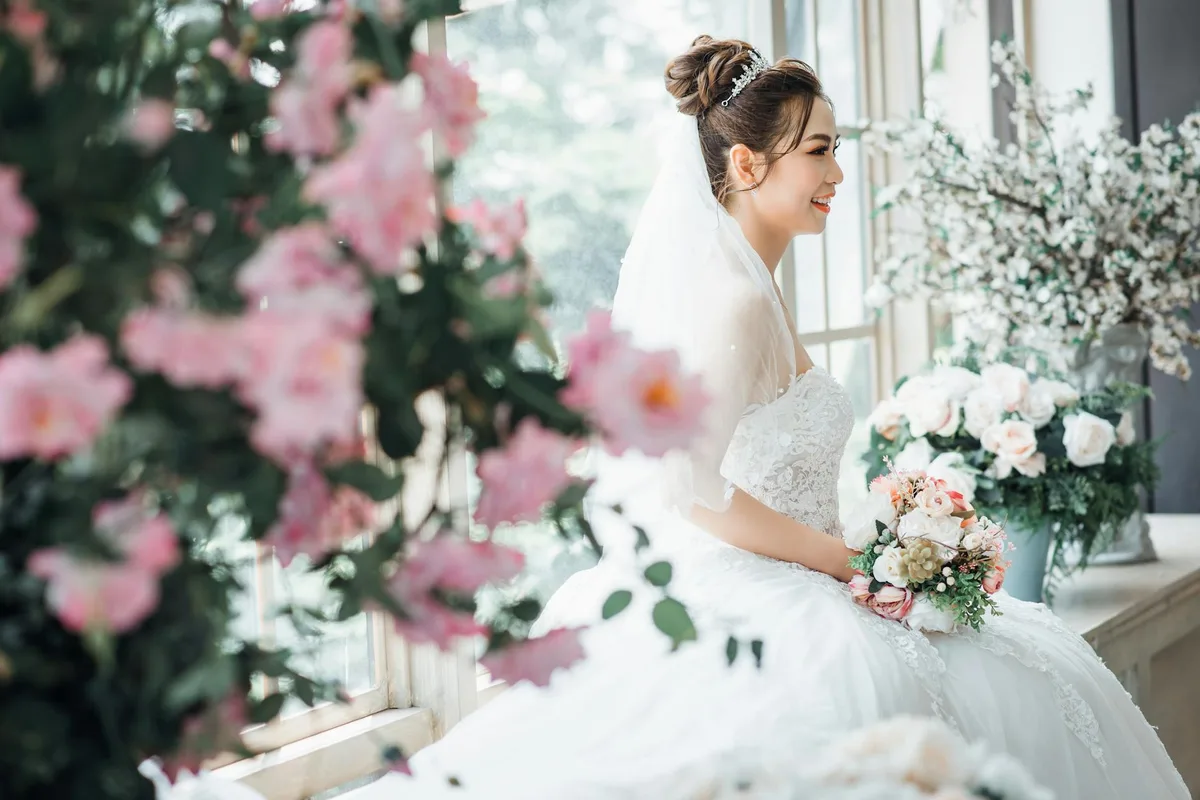 Sposa in abito bianco sorridente tra composizioni floreali eleganti
