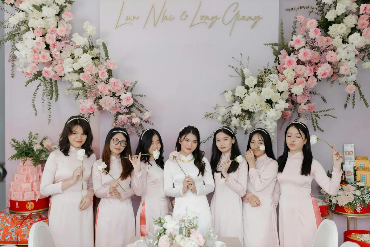 Brautjungfern in traditionellen rosa Ao Dai Kleidern mit Blumen bei Hochzeitsfeier