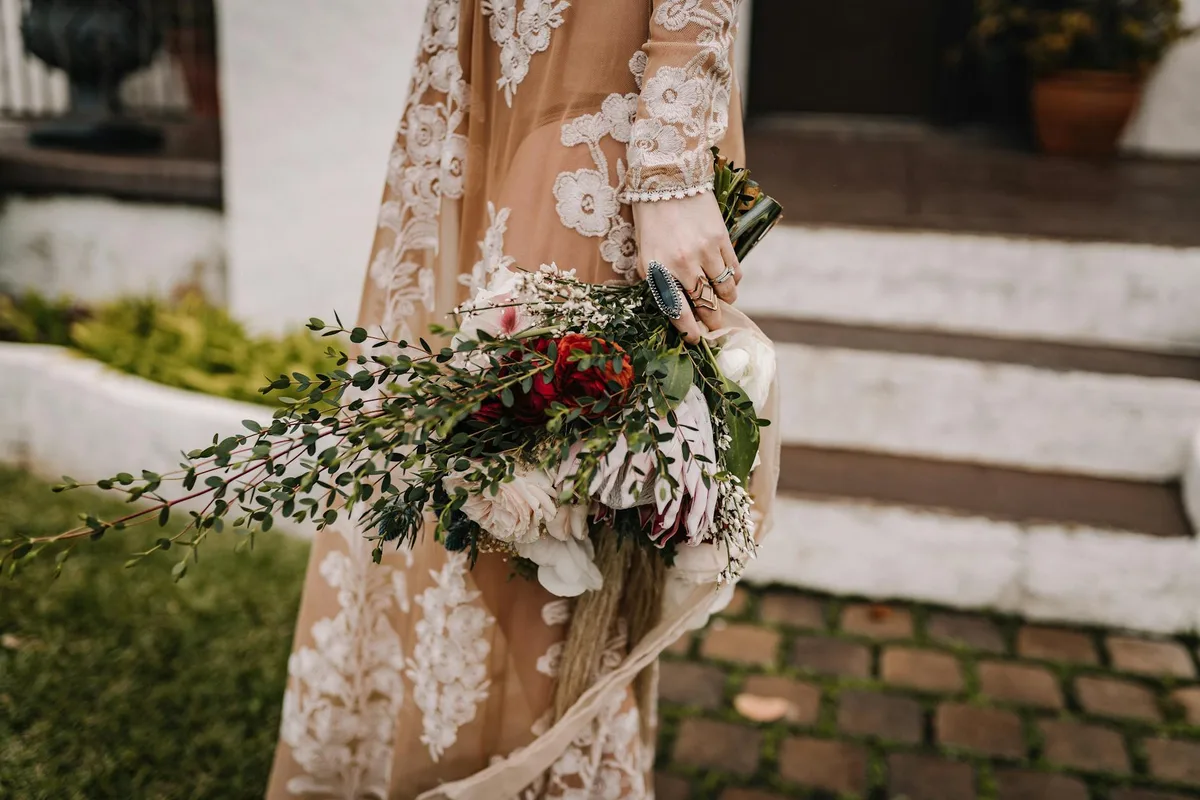 Nahaufnahme eines böhmisch-schicken Brautstraußes mit zartem Spitzenkleid