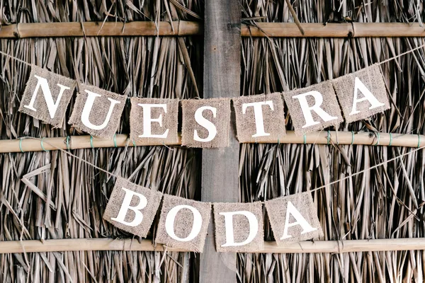 Nahaufnahme eines rustikalen Hochzeitsbanners mit Jutebuchstaben auf Stroh