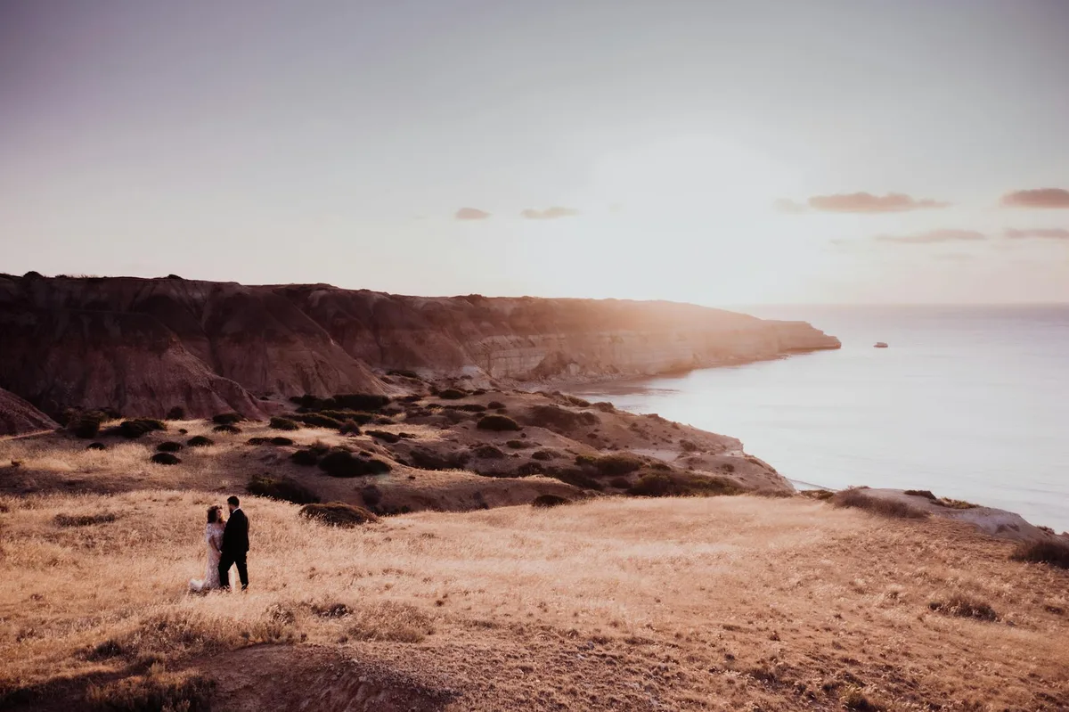 Ein Paar genießt eine romantische Hochzeit am Strand von Adelaide bei Sonnenuntergang.