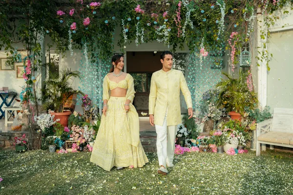 A couple in traditional attire walking through a beautifully decorated garden for a wedding ceremony.