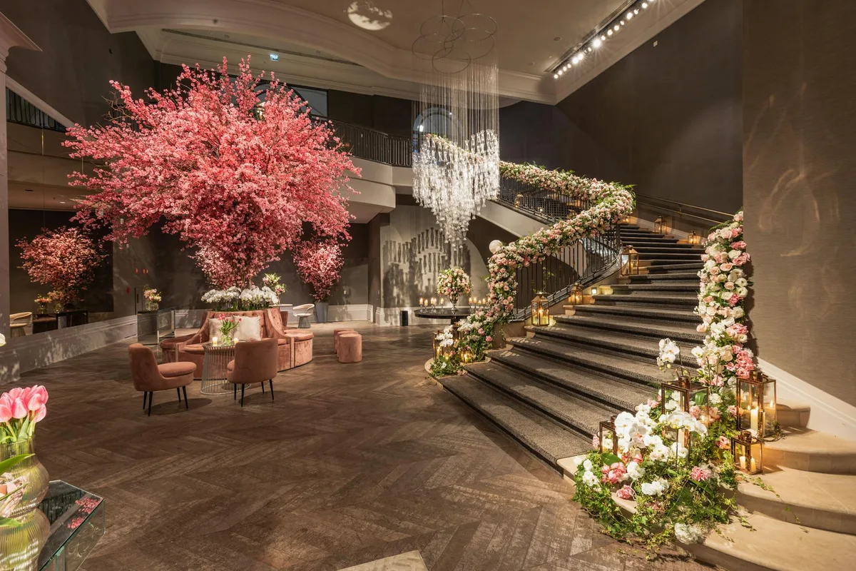 Große Hotellobby mit exquisiten Blumendekorationen, Wendeltreppe und eleganten Kronleuchtern