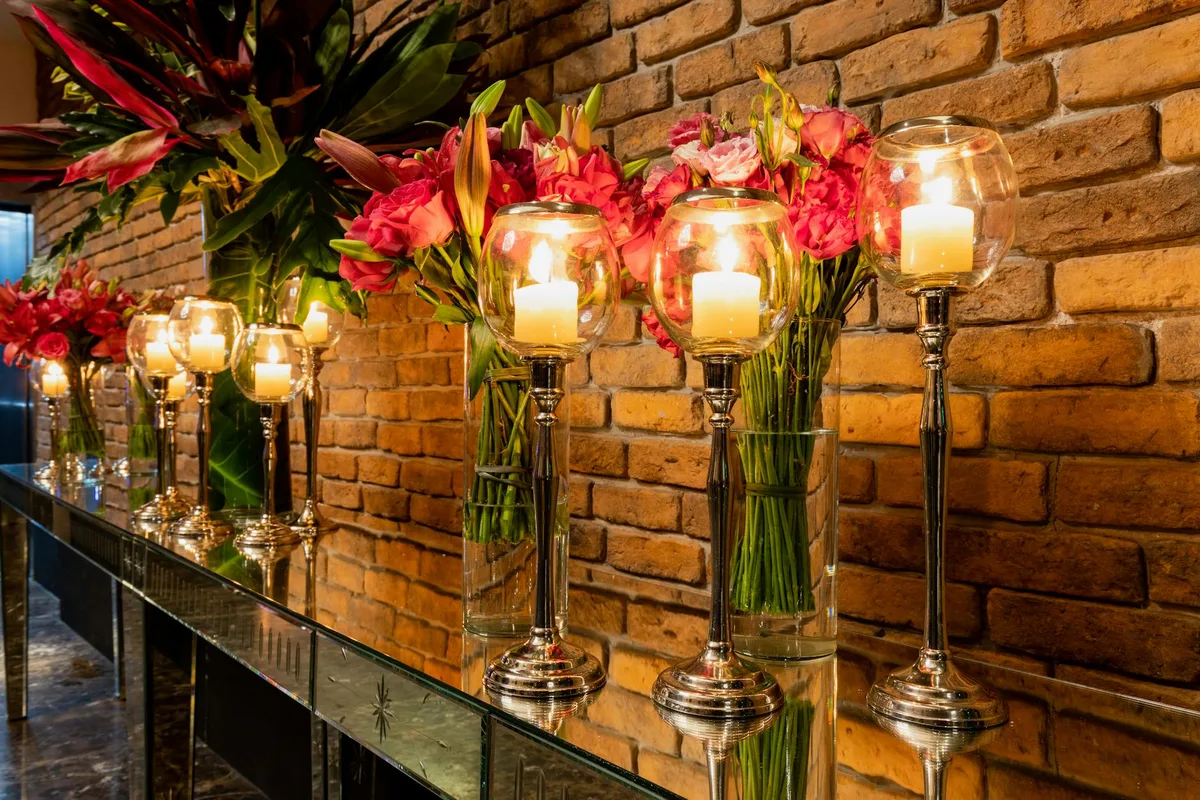 Allestimento romantico con fiori vivaci e candele contro muro di mattoni