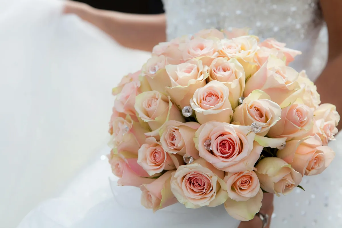 Bouquet nuziale di rose rosa tenuto da una sposa in abito da sposa, simbolo d'amore