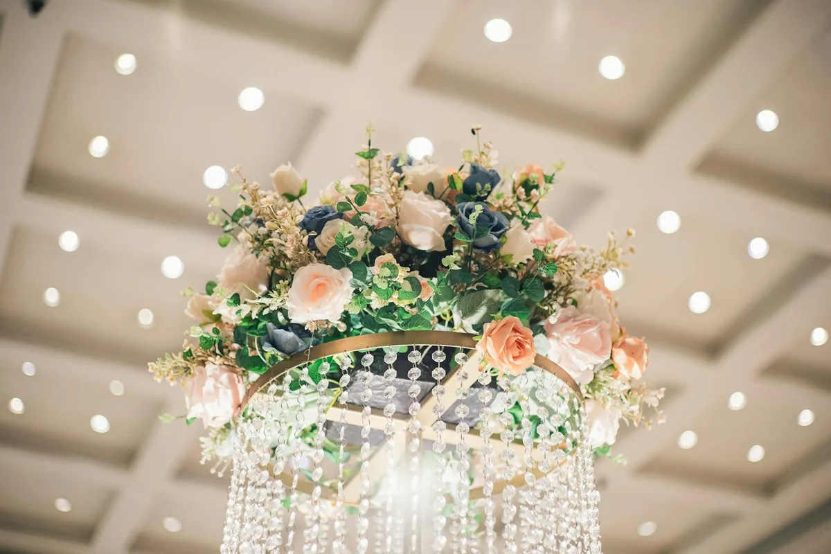 Lampadario floreale con rose e cristalli sotto luci eleganti per matrimoni