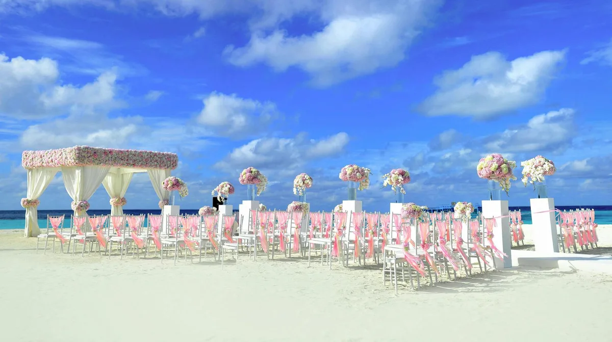 Strandhochzeit mit blauen Blumenarrangements und Sonnenschein