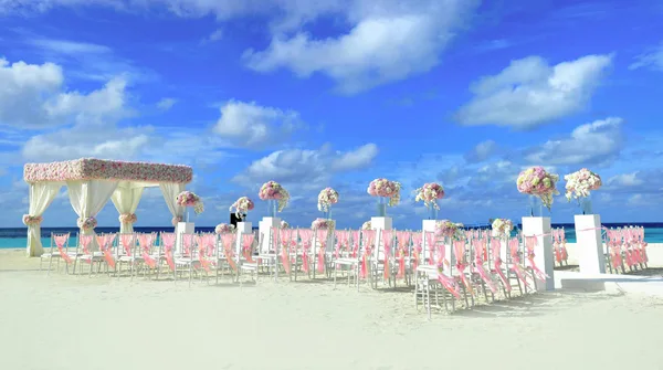 Décor de mariage sur la plage avec fleurs sous un ciel bleu vif et ensoleillé
