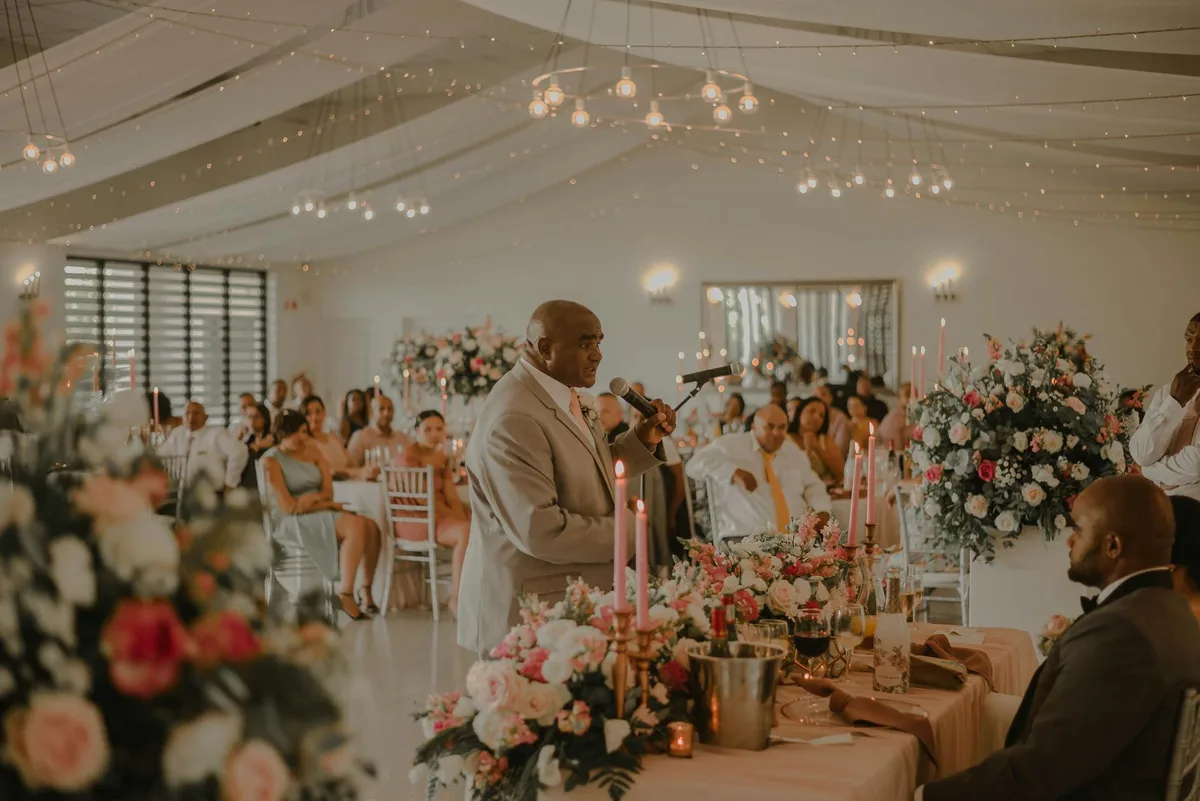 Ricevimento nuziale al chiuso con fiori e ospiti che ascoltano un discorso