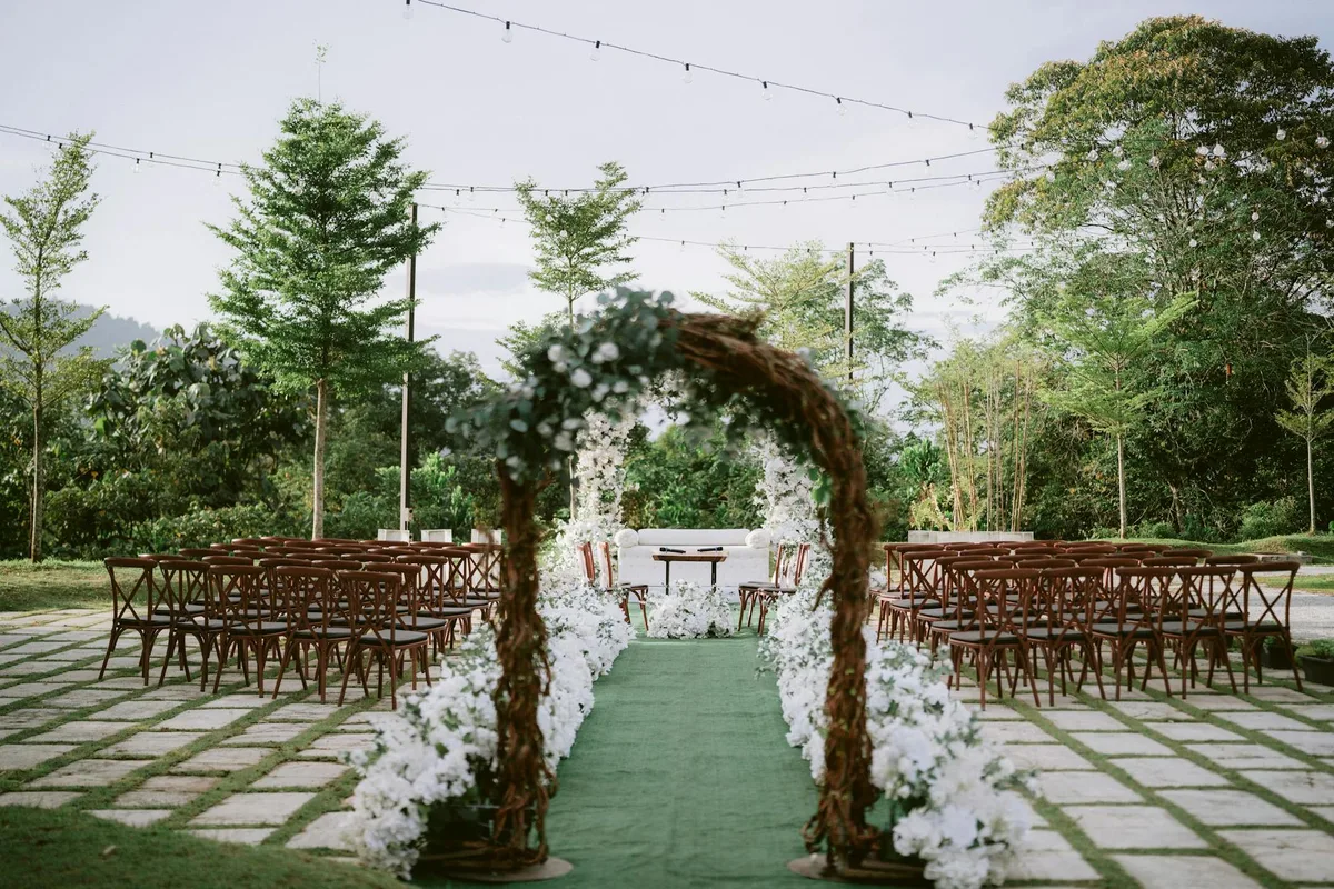 Hochzeitszeremonie mit Bogen, Stühlen und Lichtern im Garten