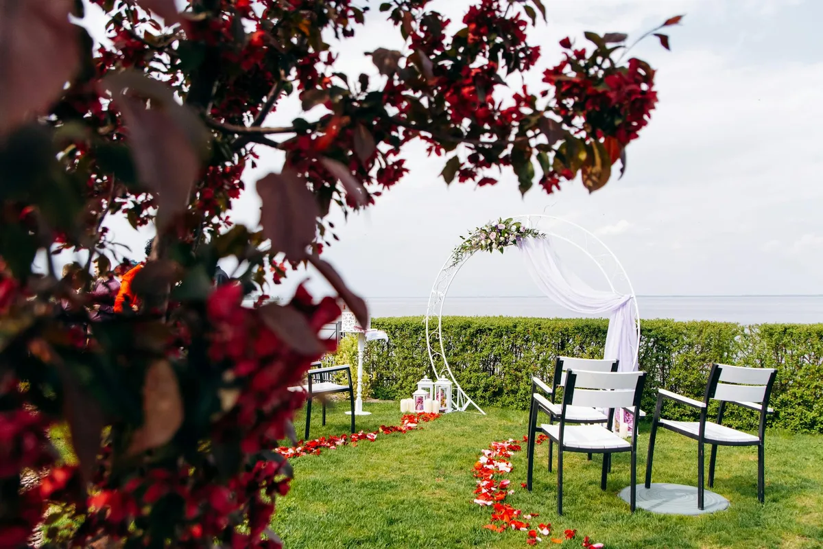 Allestimento wedding all'aperto con sedie e arco floreale sul mare
