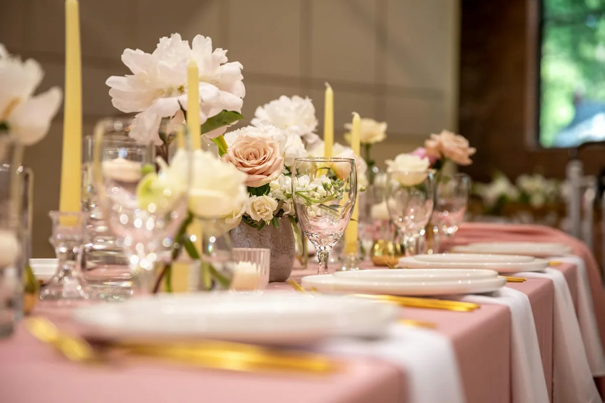 Tavolo nuziale con rose pesca e bicchieri, atmosfera romantica