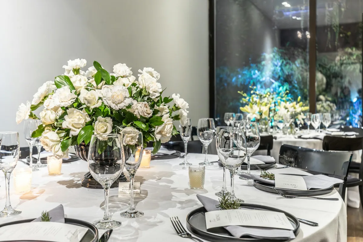 Tavolo nuziale con centrotavola floreale bianco, bicchieri e candele