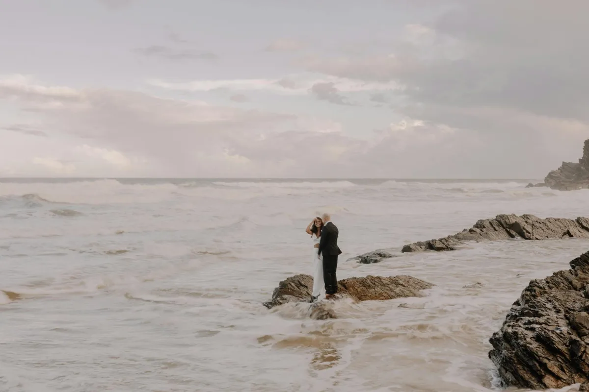 Sposi abbracciati sulla costa rocciosa a Broken Head, Australia