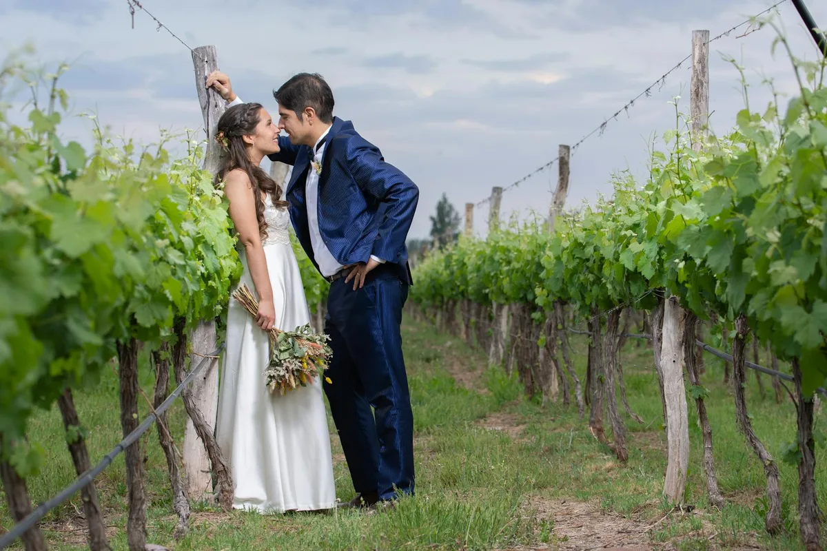 Braut und Bräutigam teilen einen romantischen Moment in einem üppigen Weinberg in Luján de Cuyo, Mendoza