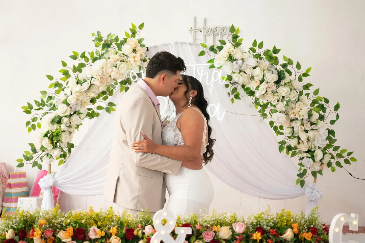 Sposi che si baciano sotto un arco floreale al loro matrimonio