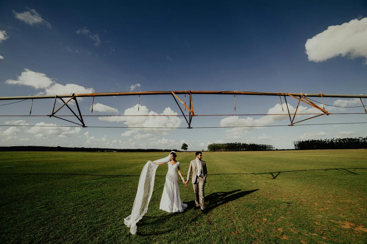 Sposi camminano insieme in un campo aperto sotto un cielo azzurro nel giorno del loro matrimonio