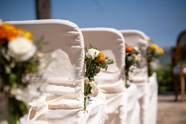 Chaises de cérémonie en extérieur avec décorations florales pour un mariage