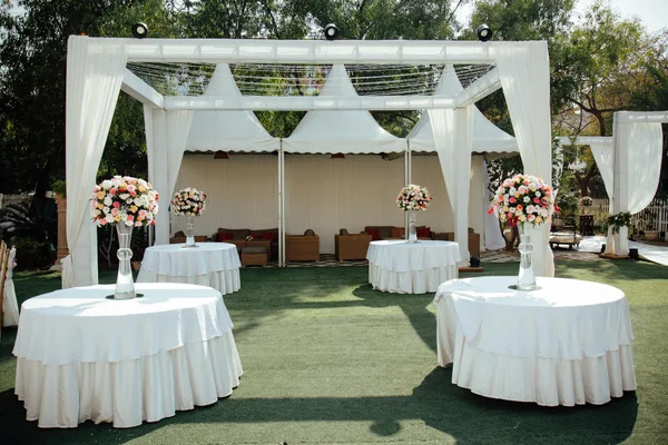 Mariage champêtre avec pergolas blanches et centres de table fleuris