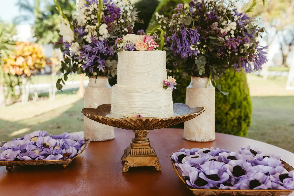 Torta nuziale bianca con fiori rosa e viola in allestimento floreale
