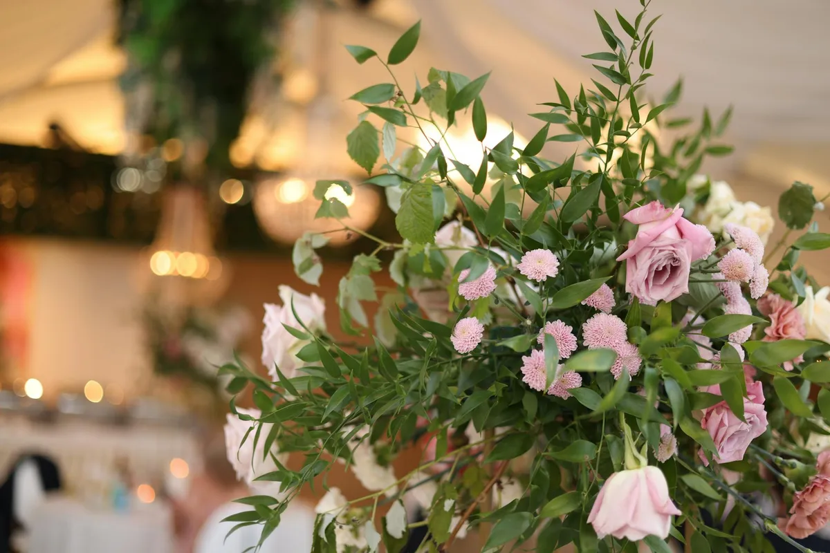 Nahaufnahme eines Blumenarrangements mit rosa Rosen bei einem Hochzeitsempfang