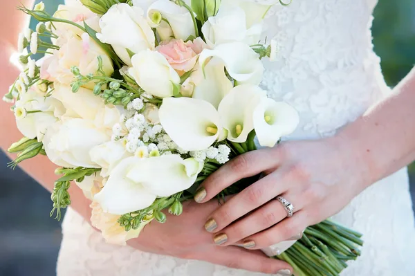 Close-up of elegant bridal bouquet with calla lilies and roses, held by bride.