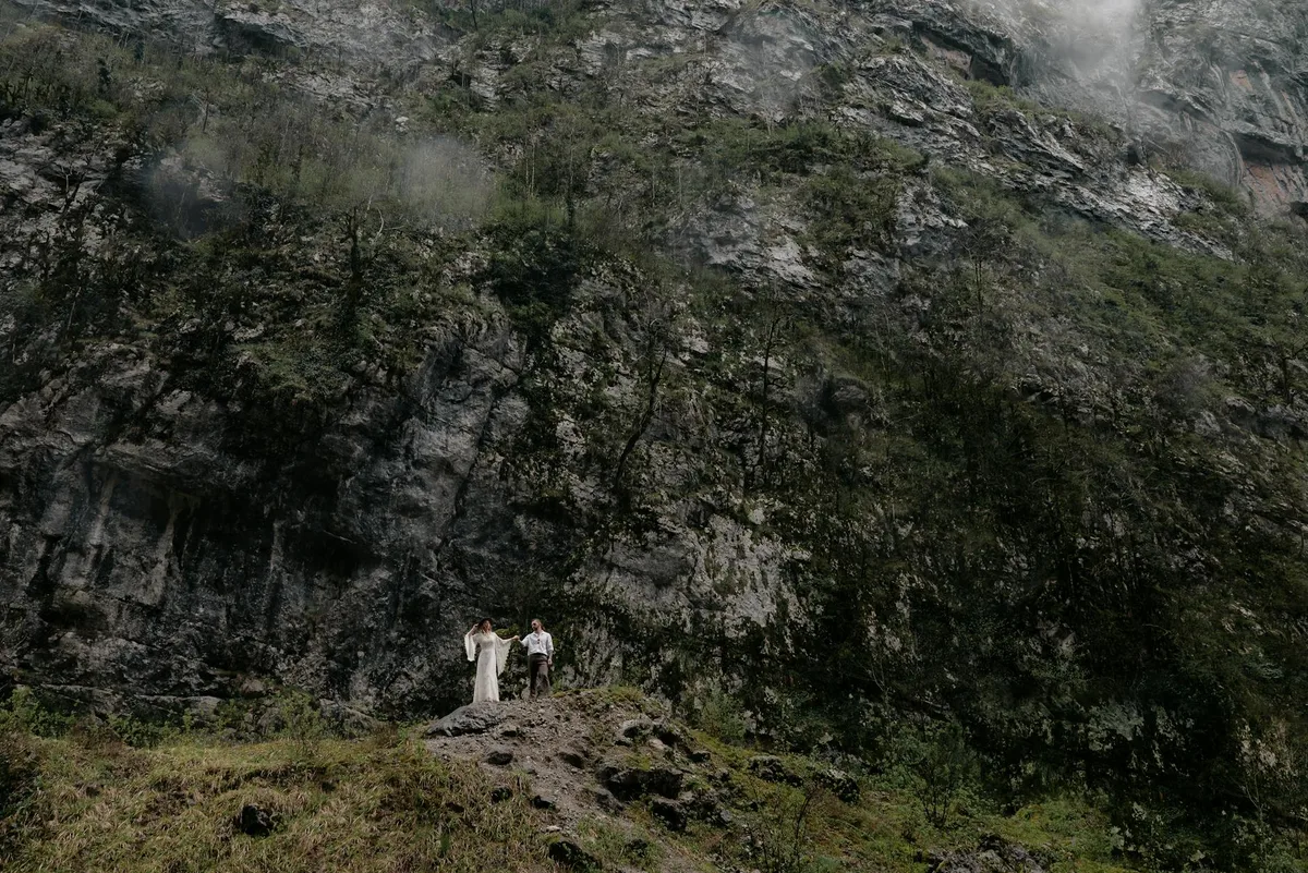 Paar in formeller Kleidung vor einer majestätischen Felswand in der Natur