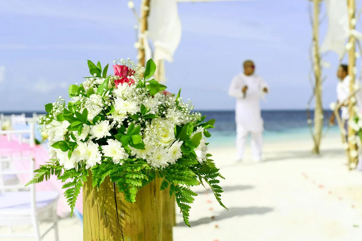 Elegante Strandhochzeit mit lebendiger Blumendekoration und Meerblick im Hintergrund