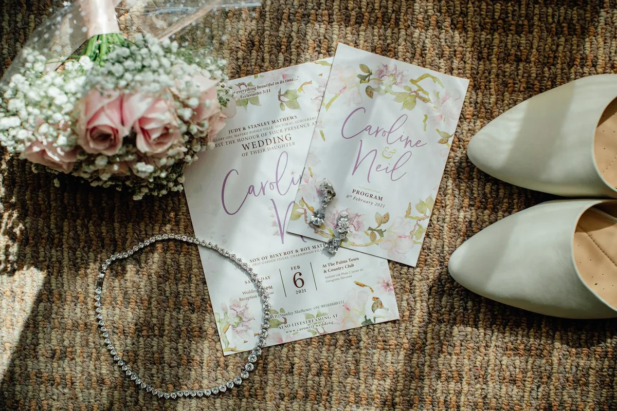 Flat lay nuziale elegante con inviti, fiori, scarpe e gioielli su superficie strutturata