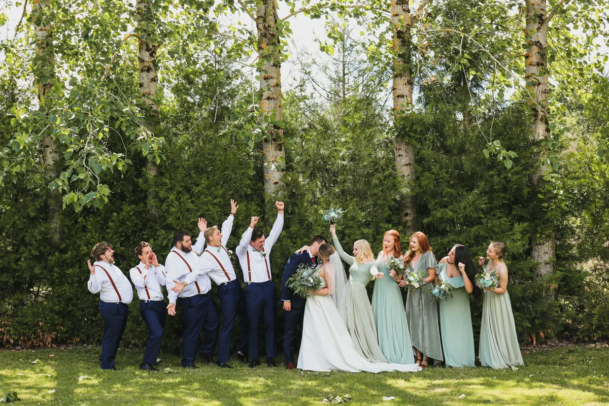 Gruppo di damigelle e testimoni all'aperto con gli sposi che si baciano