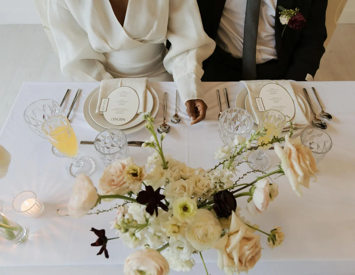 Vista dall'alto di tavolo nuziale con centrotavola floreale, cristalli e abiti formali