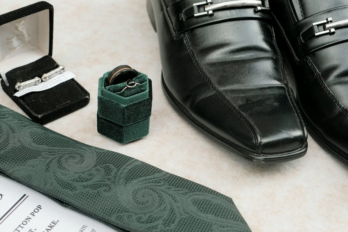 Anspruchsvolle Anordnung von Herren-Hochzeitsaccessoires wie Schuhen, Manschettenknöpfen und Ringen