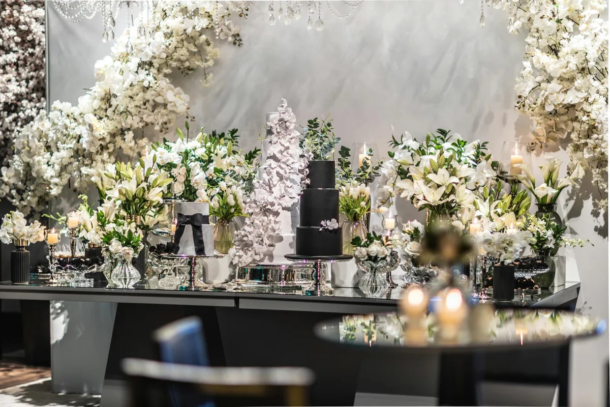 Decorazioni nuziali eleganti con fiori bianchi e torta nera in ambiente lussuoso
