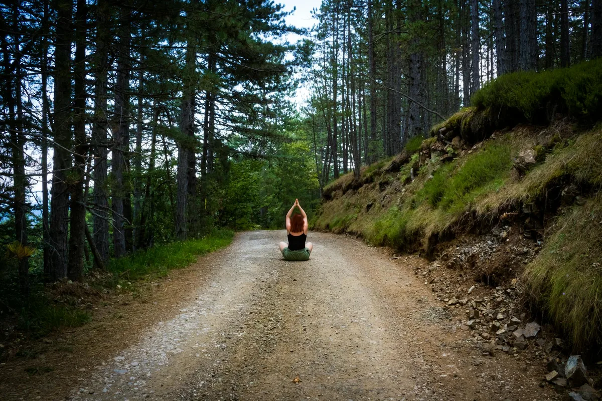 Persona in meditazione su un sentiero nel bosco in estate