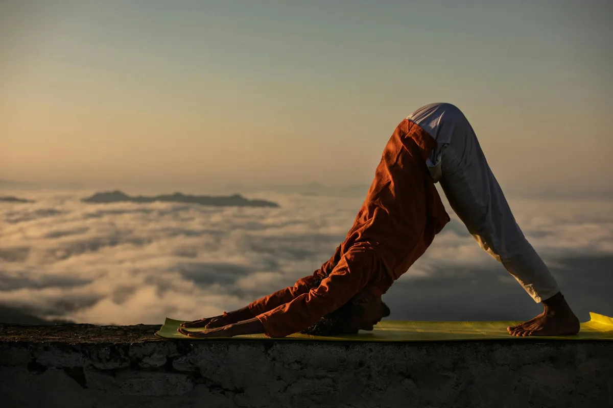 Persona pratica yoga in cima a una montagna all'alba