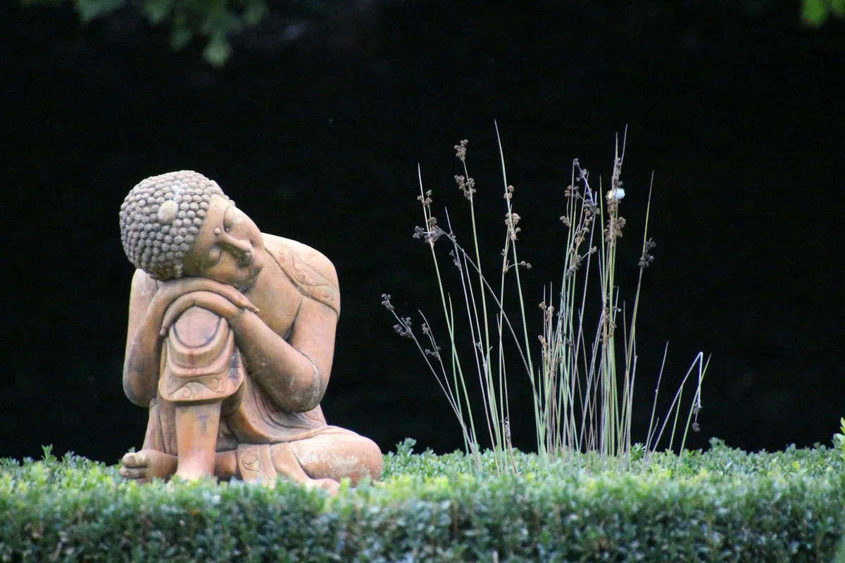 Una serena statua di Buddha riposa pacificamente in un rigoglioso giardino, evocando tranquillità e consapevolezza.