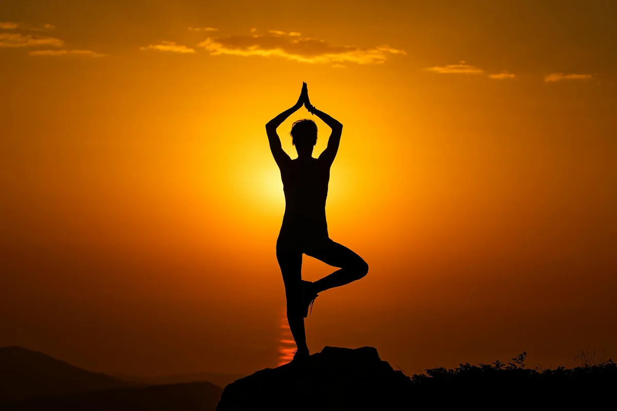 Silhouette yoga serena al tramonto su vetta montana