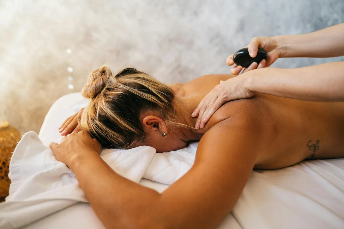 Frau genießt entspannende Heißsteinmassage-Therapie im Spa.