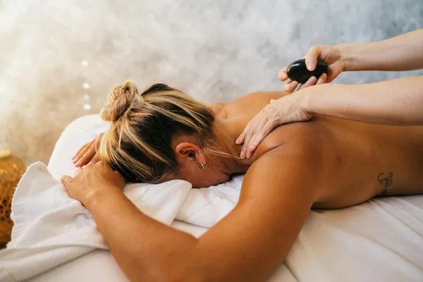 Frau genießt entspannende Heißsteinmassage-Therapie im Spa.