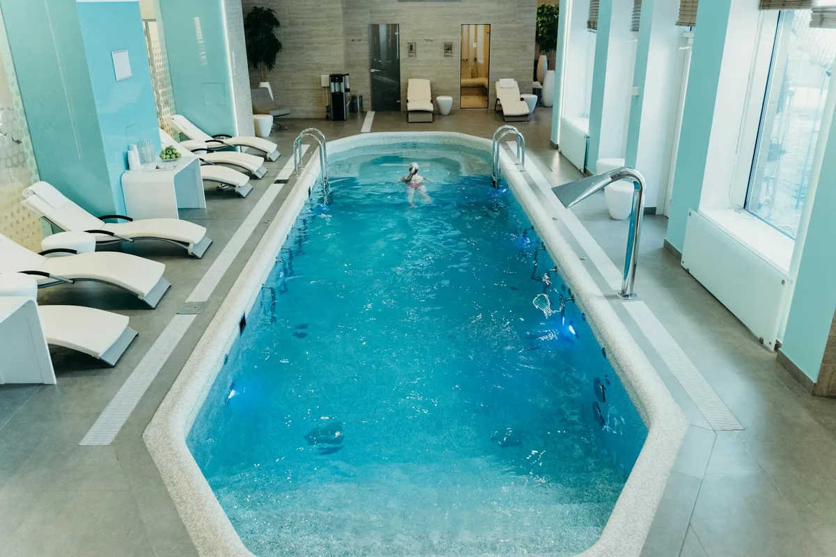 Piscina spa interna luminosa con lettini e atmosfera calma, ideale per il relax