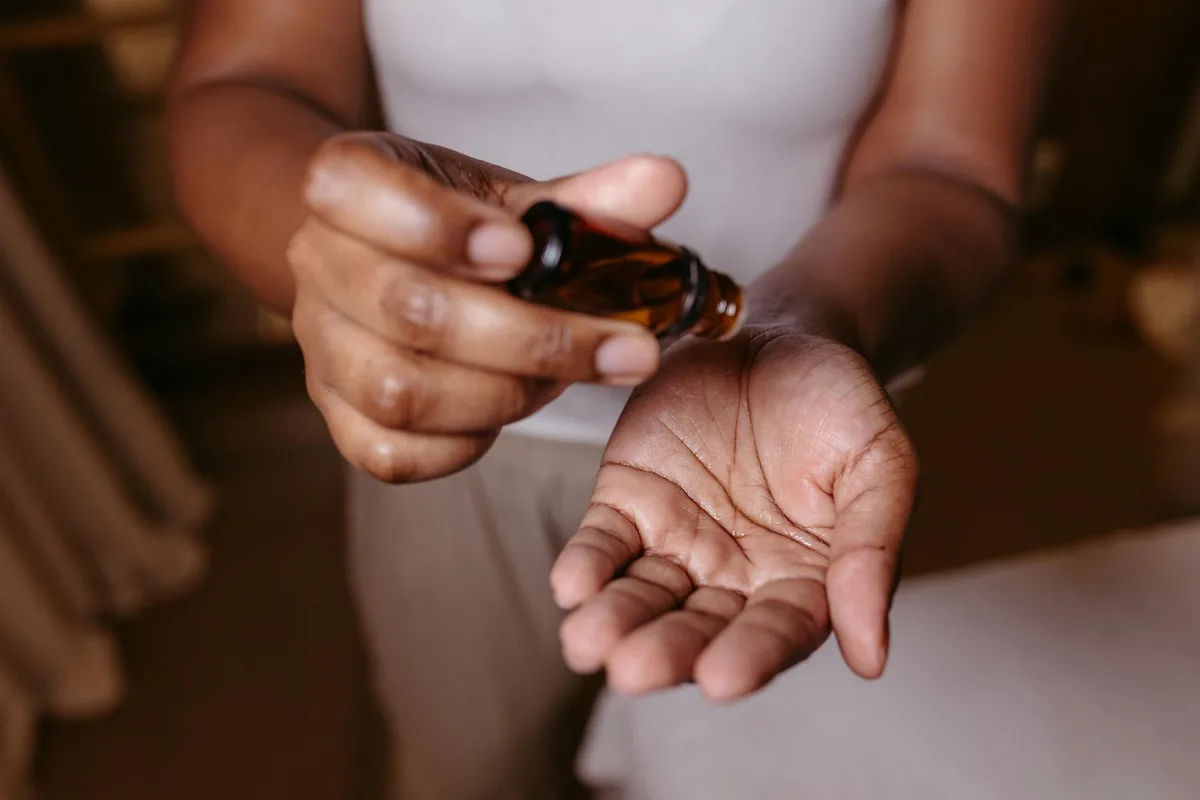 Primo piano di mani che versano olio per idratazione e skincare al chiuso.