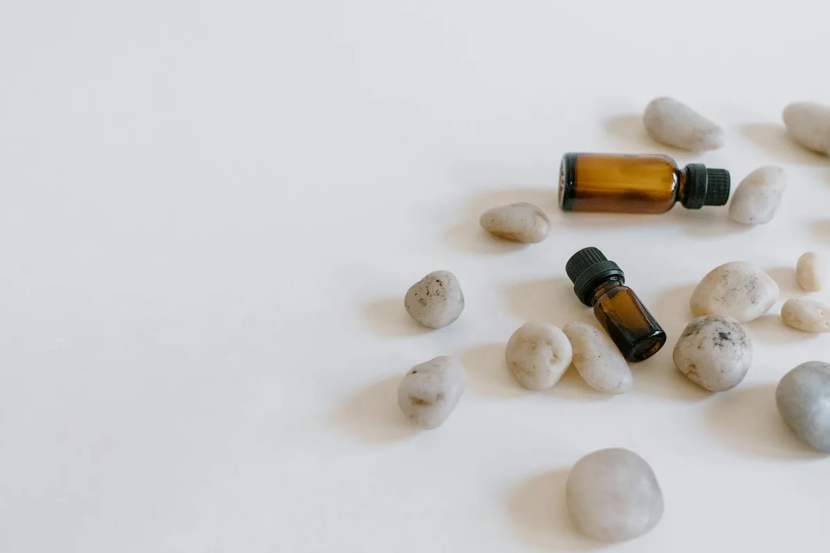 Minimalist arrangement of essential oil bottles surrounded by stones on a light background.