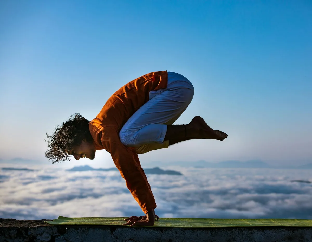 Person praktiziert Yoga auf einem Berggipfel über den Wolken