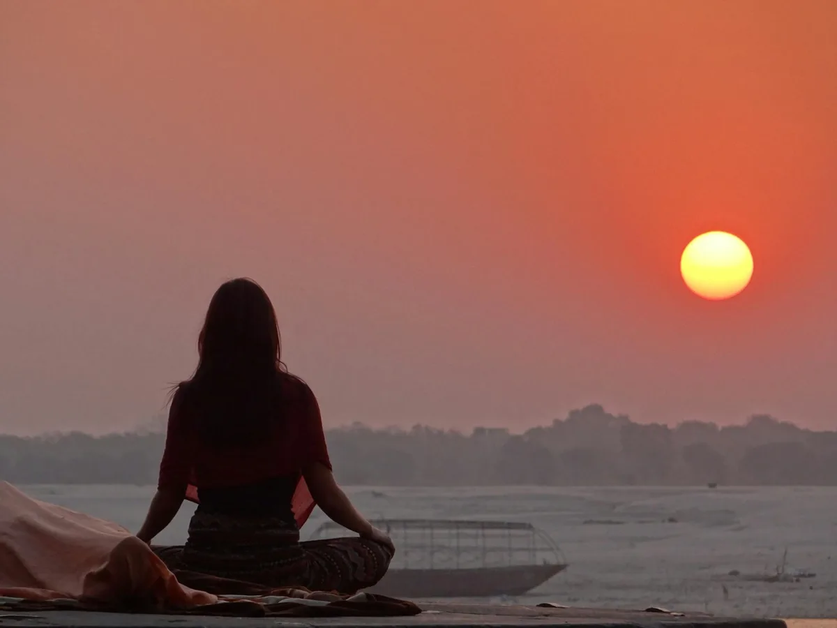 Femme méditant au coucher du soleil sur le Gange à Varanasi, Inde.