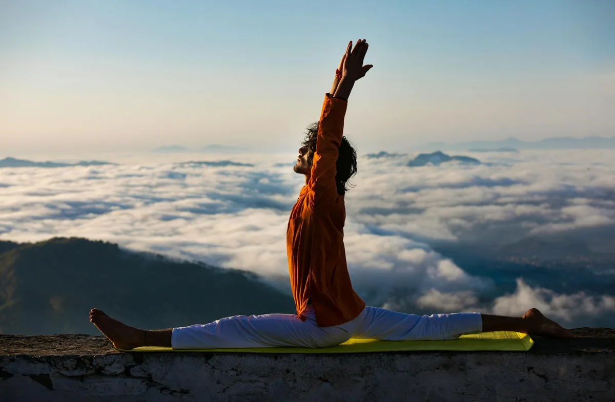 Ruhige Yoga-Pose auf Berggipfel über Wolkenmeer bei Sonnenaufgang