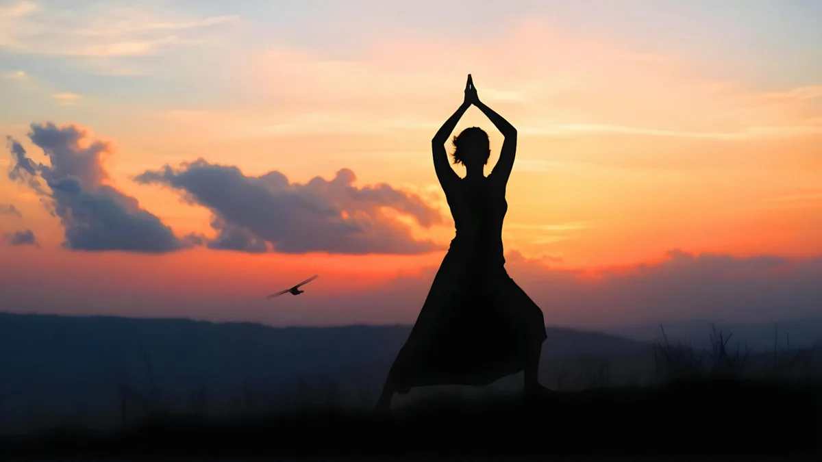 Silhouette einer Frau beim Yoga bei ruhigem Sonnenuntergang im Freien.