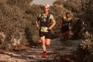 Two men trail running on a rugged rural path, engaged in a competitive race.